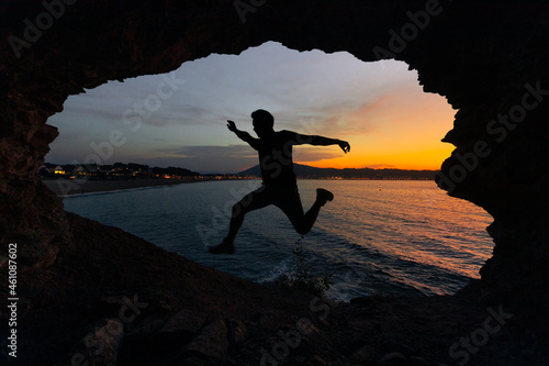 Young man silhouette in a coastal cave next to Hendaia beach, at the Basque Country.