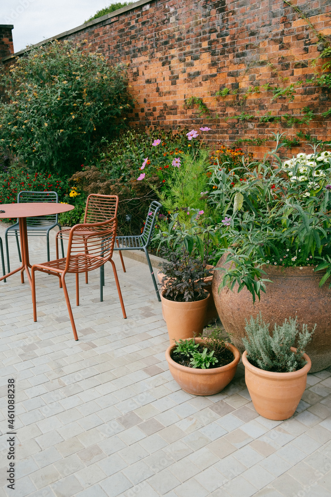 Outdoor cafe table and chair in a relaxing garden, surrounded by plants and flora.