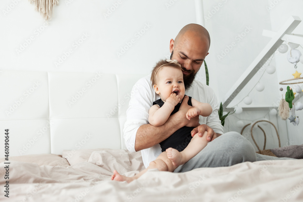 Caring father plays with his little daughter on the bed in bedroom. Love and care, happy family, spending time together concept Caring father plays with his little daughter on the bed in bedroom. Love and care, happy family, spending time together concept