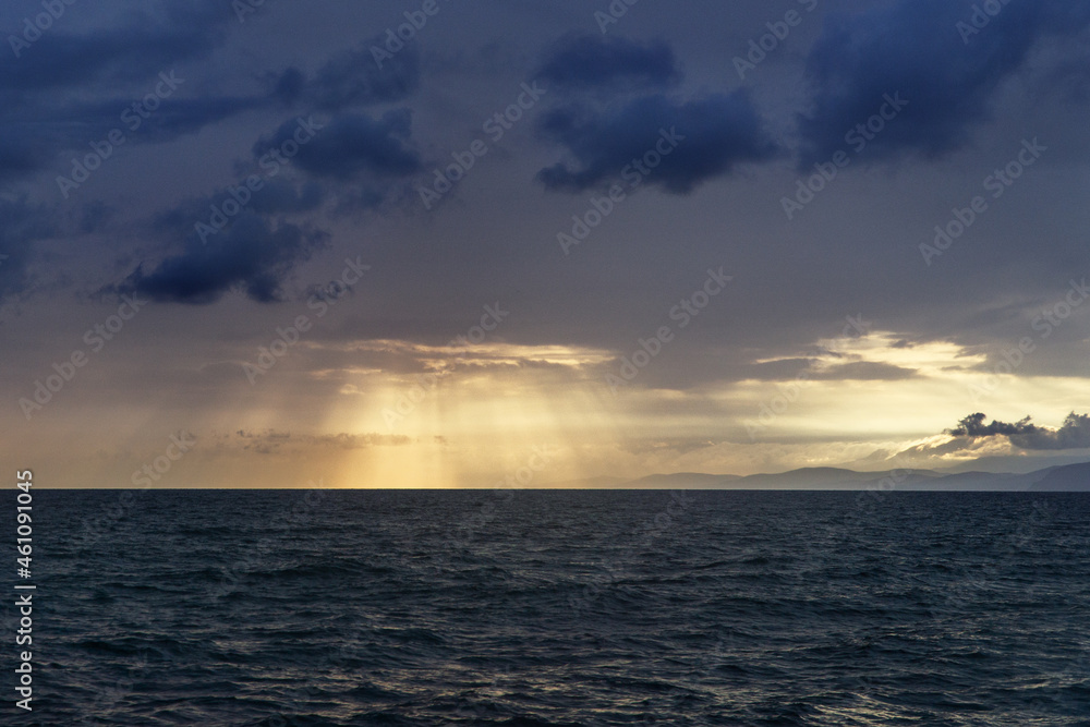 the setting sun shines through the clouds over the Black Sea