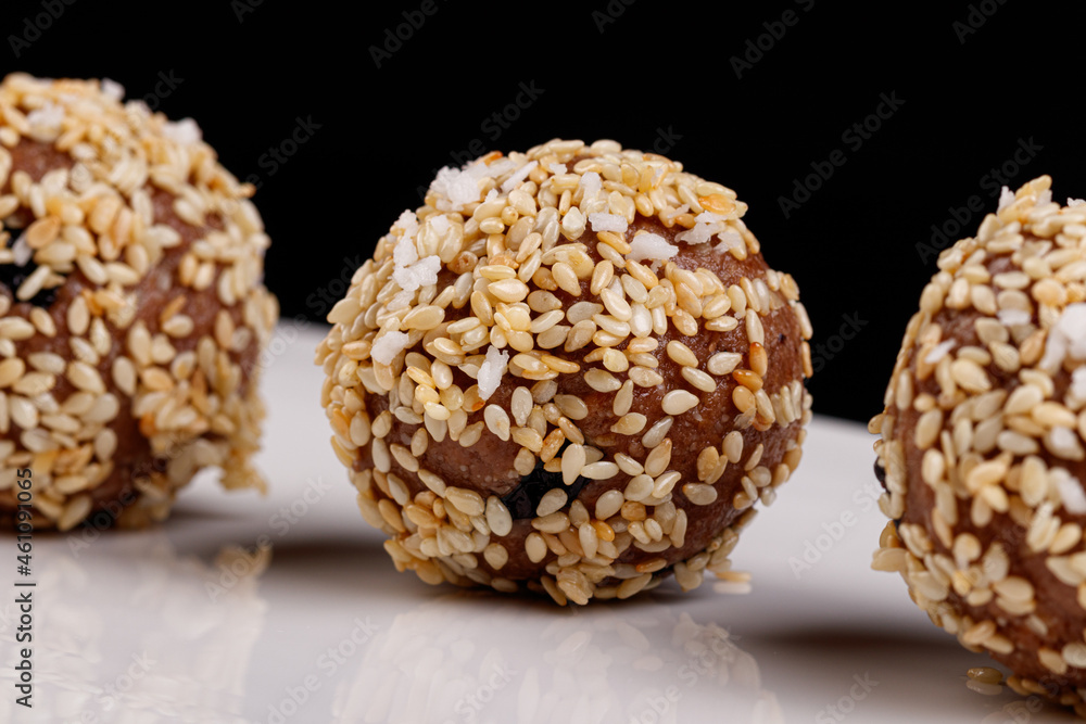 Beautiful candies with sesame seeds on a white plate on a black background Beautiful candies with sesame seeds on a white plate on a black background