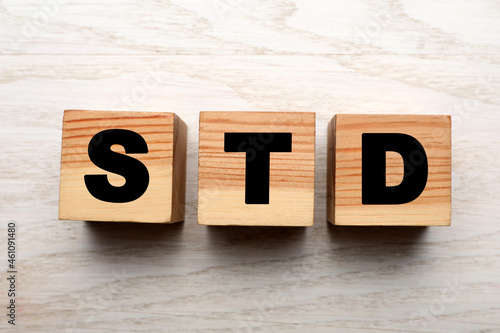 Abbreviation STD made with cubes on white wooden table, flat lay