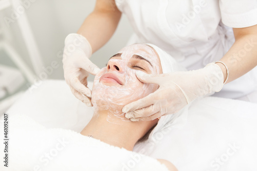 Facial skin care procedures. Beautician makes massage procedure with beauty woman s face in cosmetic clinic
