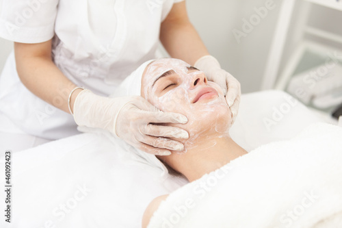 Facial skin care procedures. Beautician makes massage procedure with beauty woman's face in cosmetic clinic