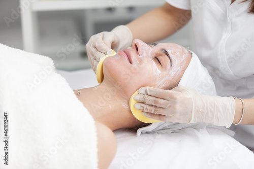 Facial massage and skincare treatment. Dermatologist hands cleaning relaxed serene young woman face with pads in beauty salon during skincare treatment. Face massage