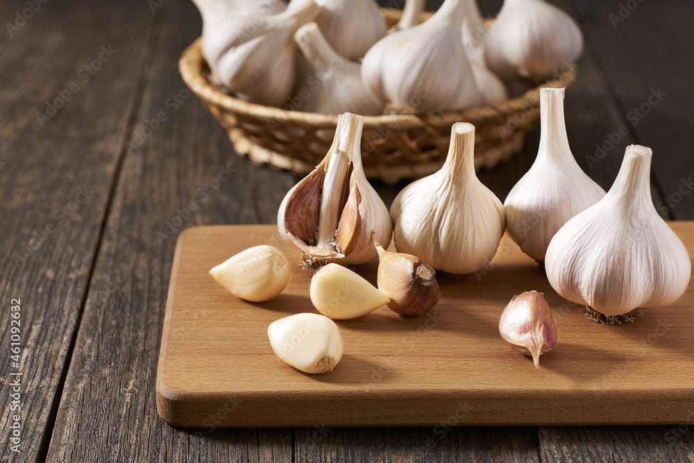 Peeled and unpeeled garlic cloves on a cutting board. Peeled and unpeeled garlic cloves on a cutting board.