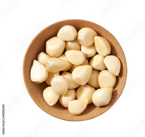 peeled garlic cloves in a wooden bowl isolated on white background, top view.
