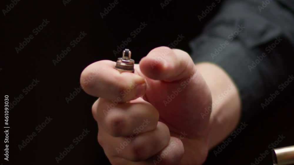 Person hands take off lid of modern metal tourist lighter standing on black background close view motion around Person hands take off lid of modern metal tourist lighter standing on black background close view motion around