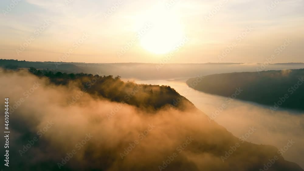 Morning summer landscape. Aerial view from a height of the sunrise landscape over the river. Fog over the river and orange sun illuminating the fog. Relaxation and meditation. Morning summer landscape. Aerial view from a height of the sunrise landscape over the river. Fog over the river and orange sun illuminating the fog. Relaxation and meditation.