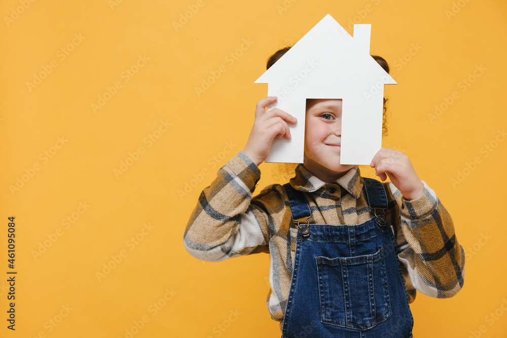 Pretty playful kid girl holding paper house, homeless housing and home protection insurance concept, international day of families, foster home care, family day care, isolated on yellow background Pretty playful kid girl holding paper house, homeless housing and home protection insurance concept, international day of families, foster home care, family day care, isolated on yellow background