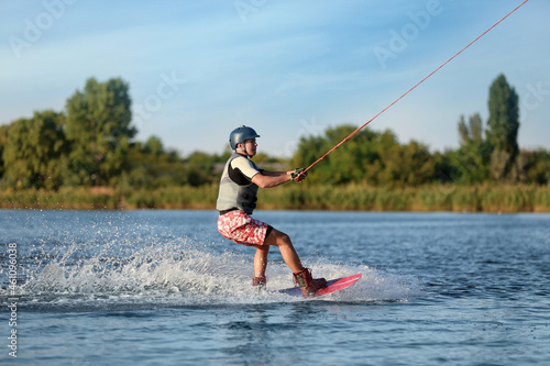 Teenage boy wakeboarding on river. Extreme water sport