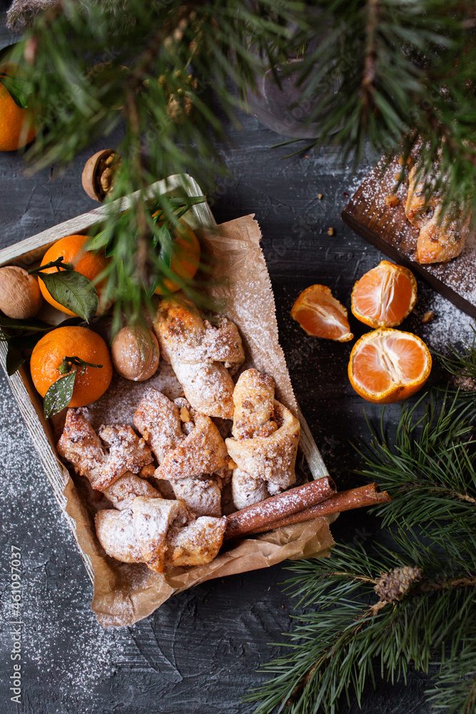 Christmas bagels with nuts. croissants. Tangerines and pastries on a gray background. New Year's atmosphere. Hazelnuts and walnuts. Bagels with cinnamon in a box.