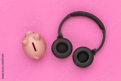 Piggy bank and stereo headphones on pink background. Top view