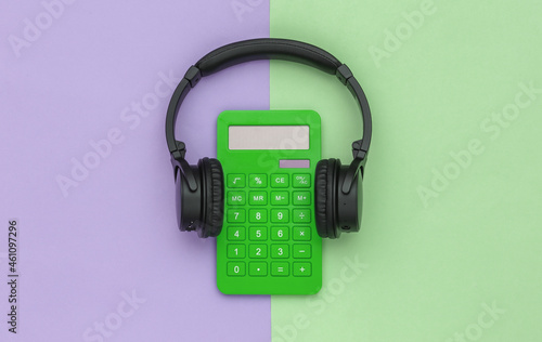 Calculator with headphones on purple green pastel background. Top view