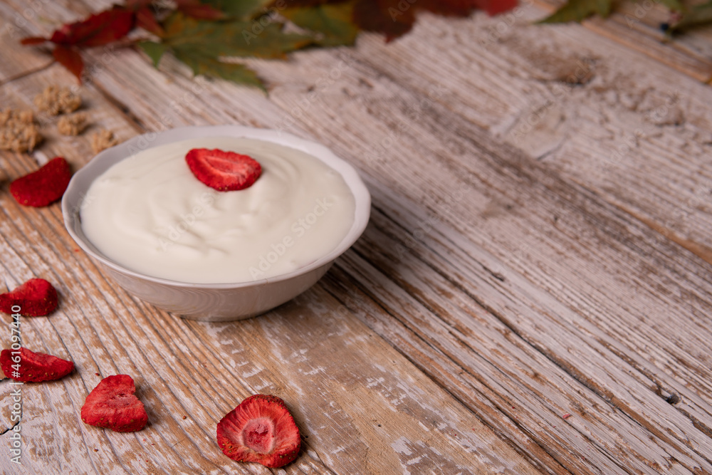 Healthy breakfast on wooden table. natural yogurt with dehydrated strawberries on a wooden background top view