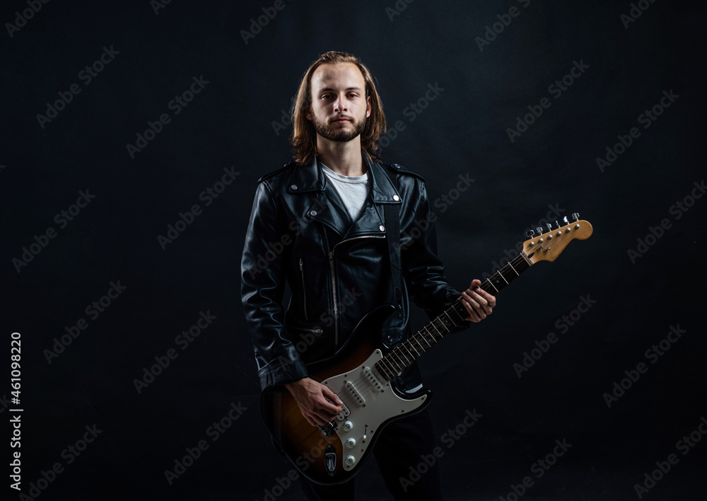 Obraz premium bearded rock musician playing electric guitar in leather jacket, guitarist