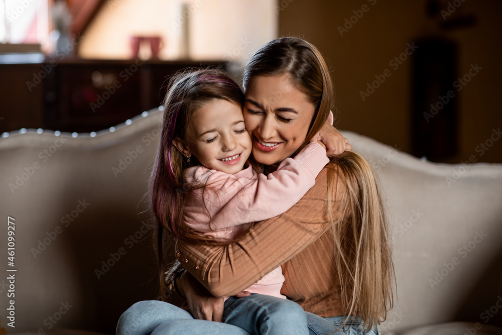 Portrait of happy woman and daughter hugging on couch Portrait of happy woman and daughter hugging on couch