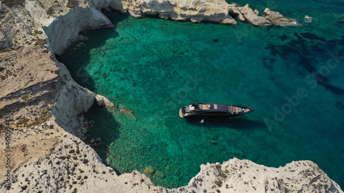 Aerial drone photo of luxury yacht anchored near famous white chalk volcanic bay of Sarakiniko, Milos island, Cyclades, Greece