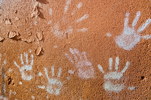 Multiple colorful children hand prints on huskily brown wall photo