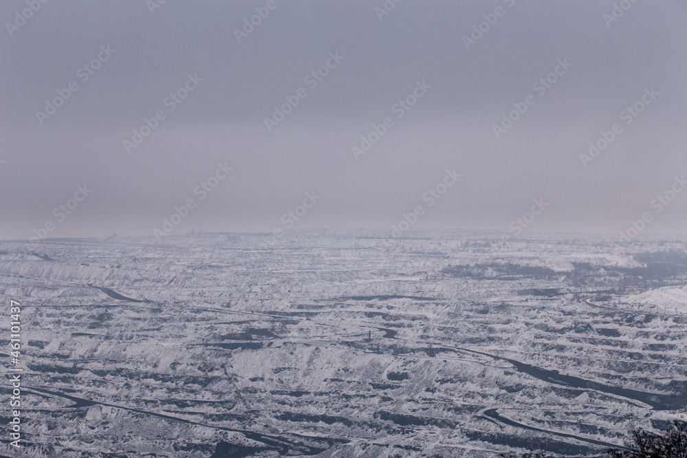 Iron ore quarry horizons covered with snow in winter, mining process in winter in cloudy weather Iron ore quarry horizons covered with snow in winter, mining process in winter in cloudy weather