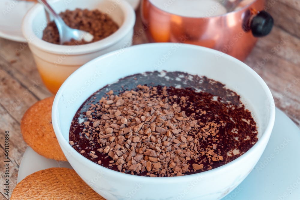 Bowl with milk and soluble coffee being diluted, with cookies and a container with sugar. Breakfast concept with soluble coffee. Bowl with milk and soluble coffee being diluted, with cookies and a container with sugar. Breakfast concept with soluble coffee.