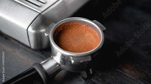 Holder for the coffee machine. Horn espresso coffee maker. Coffee beans. Preparation of espresso. Silver coffee machine and a horn with ground grains on the wooden table