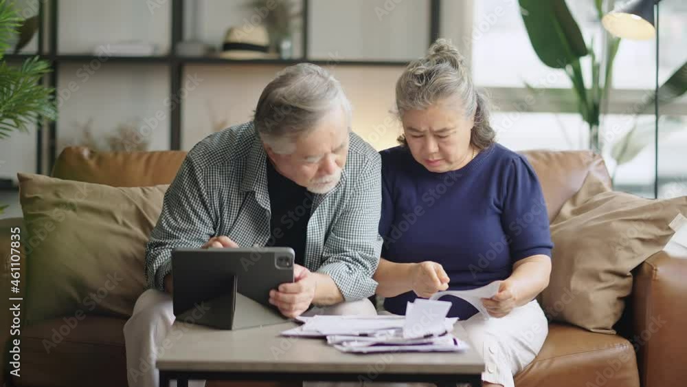 old retired asian senior couple checking and calculate financial billing together on sofa involved in financial paperwork, paying taxes online using e-banking laptop at living room home background old retired asian senior couple checking and calculate financial billing together on sofa involved in financial paperwork, paying taxes online using e-banking laptop at living room home background