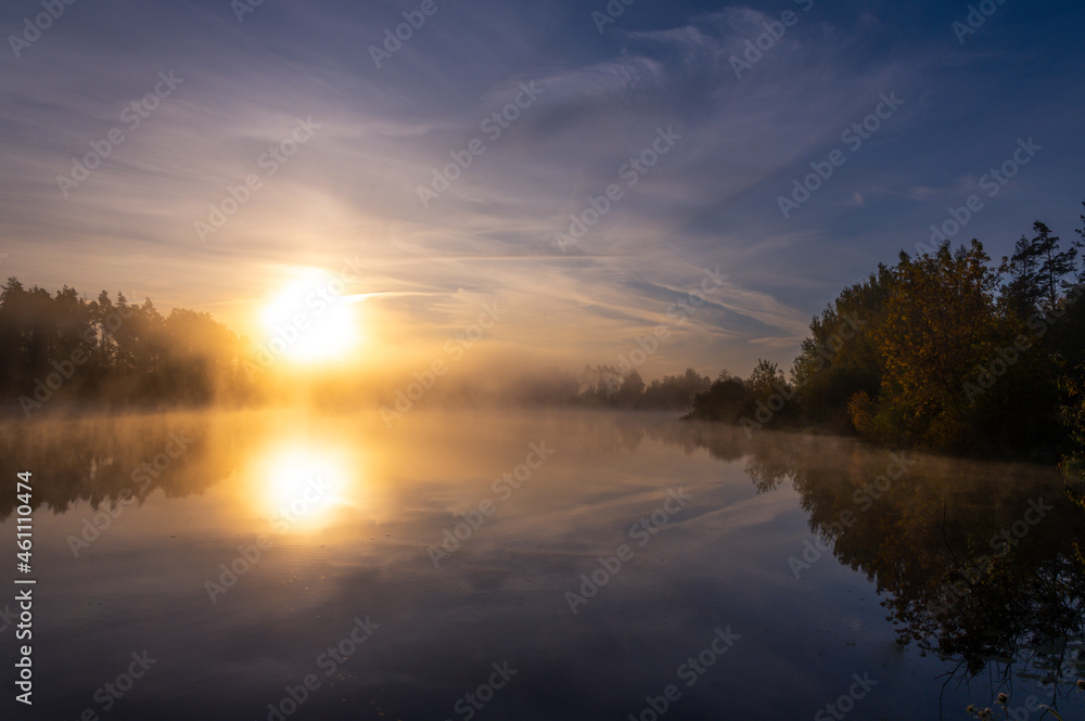 Foggy lake landscape, clouds and vibrant autumn colors in trees at dawn Concepts: tranquility, nature, background, morning