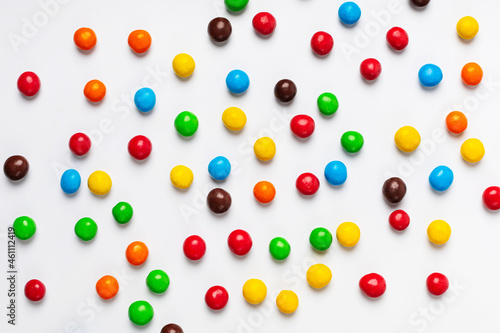 Scattering of multicolored chocolate pills background on white