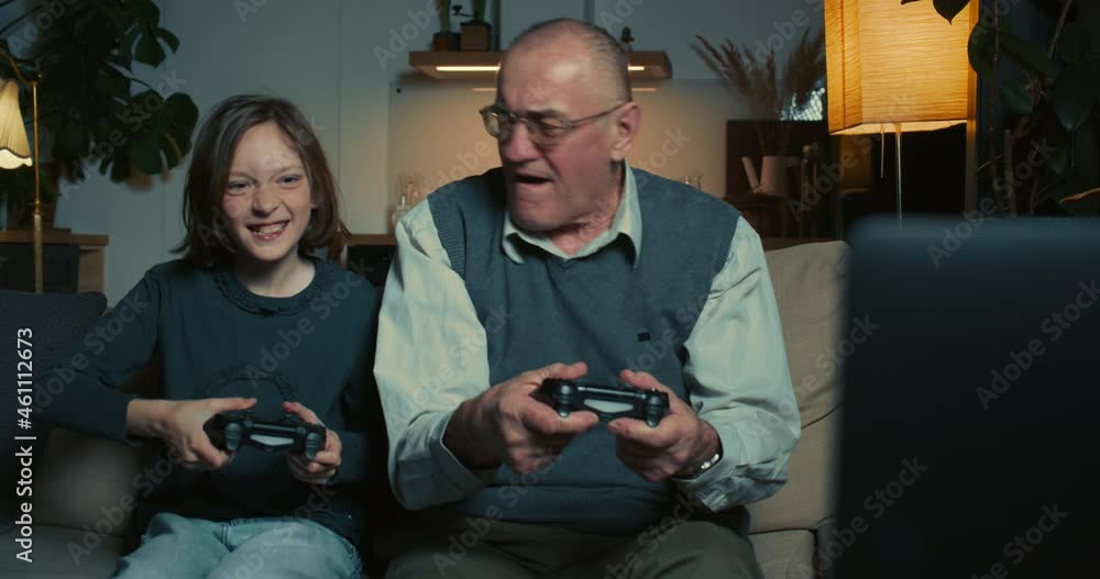 Happy excited cute teen girl having fun playing console video game using joysticks with old senior 60s grandfather. Happy excited cute teen girl having fun playing console video game using joysticks with old senior 60s grandfather.