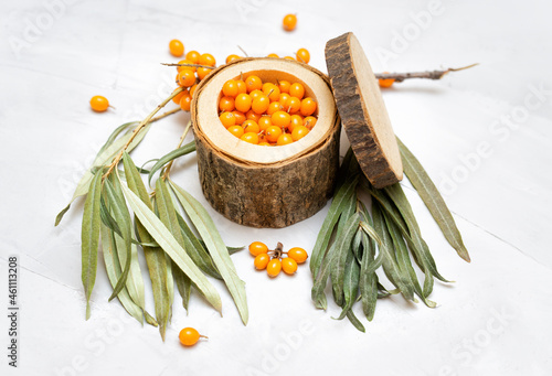 Ripe seaberries in a wooden bowl on a neutral background photo