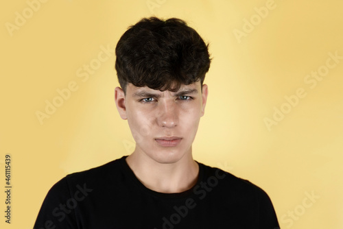 A teenage boy with a tired sad face on a yellow background, the guy has problems with his parents and he is very worried and has a headache