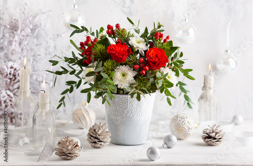 Fotografie Festive winter flower arrangement with red roses, white chrysanthemum and berries in vase on table