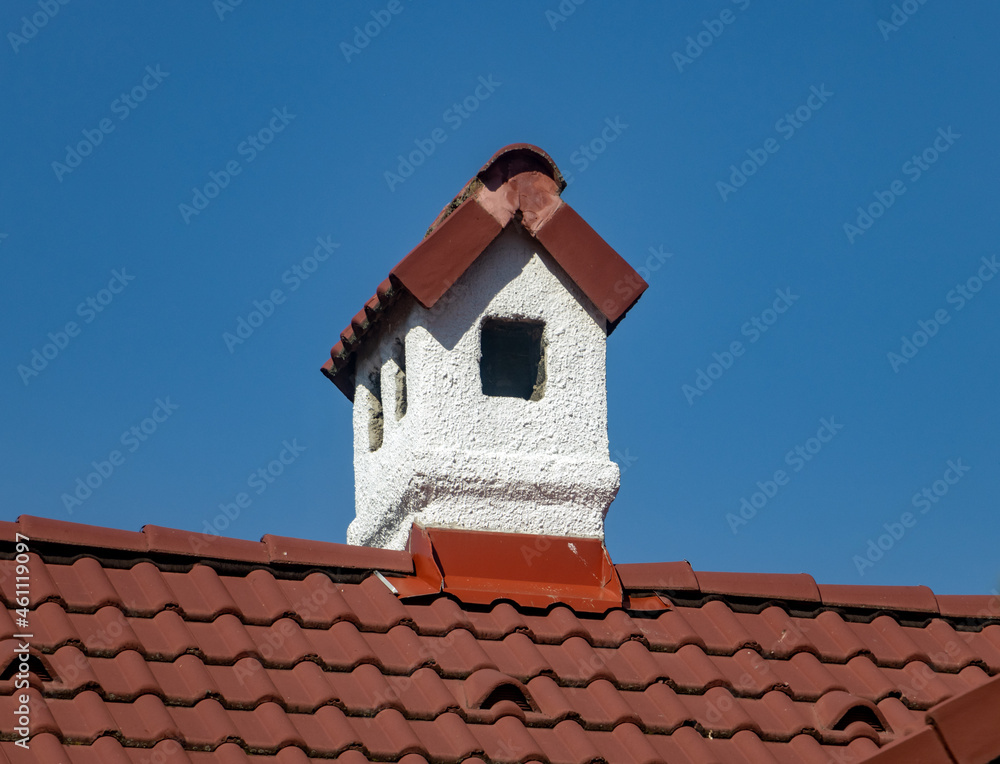A white chimney on the roof of red tiles