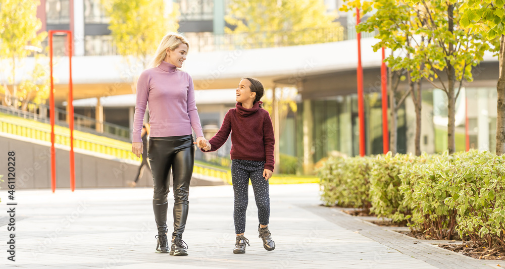 Little girl and her mother enjoy sunny weather in the autumn park