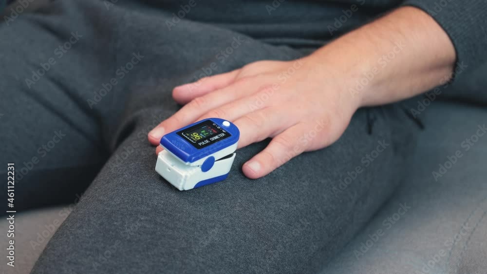 Man using the digital pulse oximeter on a finger, medical monitoring and showing oxygen saturation level on display, close up view Man using the digital pulse oximeter on a finger, medical monitoring and showing oxygen saturation level on display, close up view