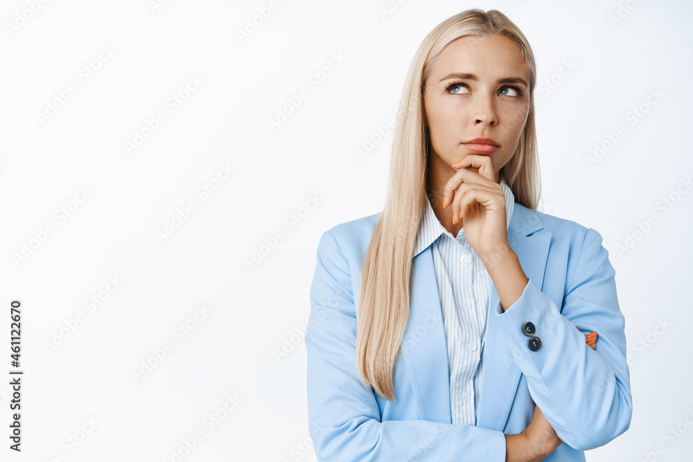 Image of thoughtful corporate woman looking aside, thinking with serious face, standing in suit over white background Image of thoughtful corporate woman looking aside, thinking with serious face, standing in suit over white background