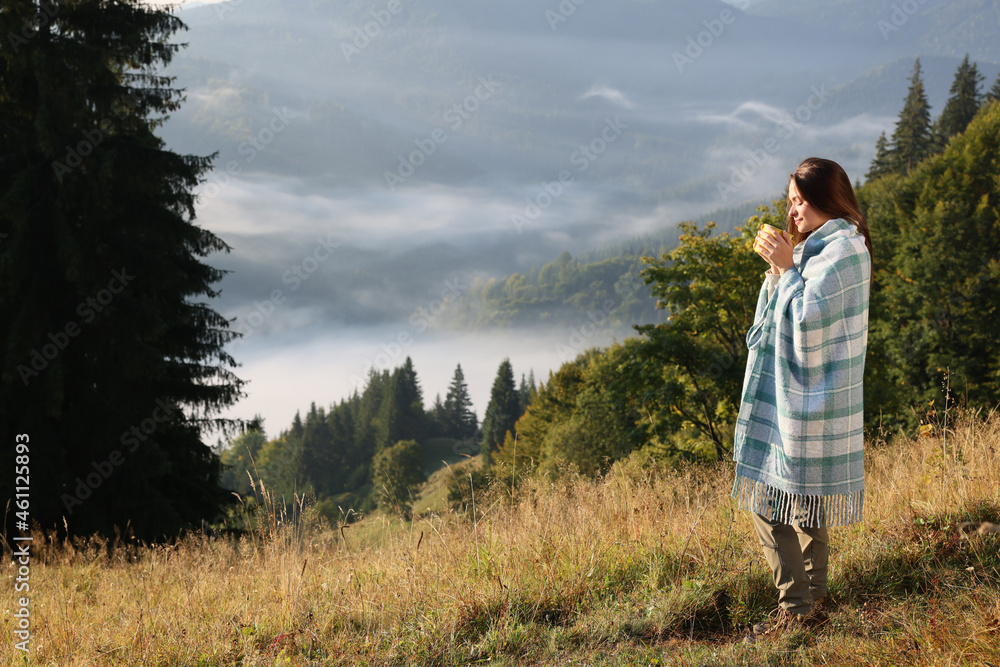 Woman with cozy plaid enjoying cup of hot beverage in nature Woman with cozy plaid enjoying cup of hot beverage in nature