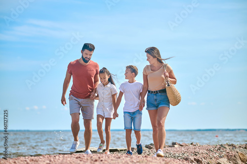 A family walking on a shore holding hands