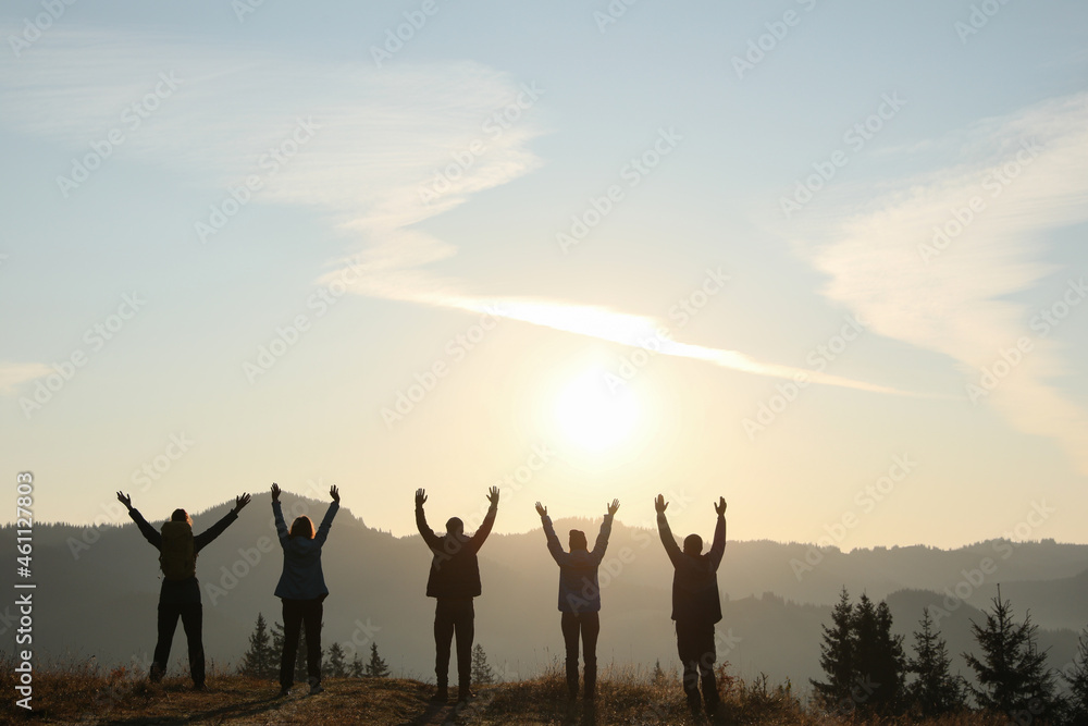 Group of people enjoying sunrise in mountains, back view. Space for text