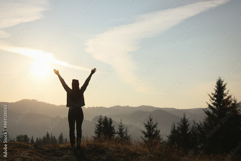 Silhouette of woman at sunrise in mountains, back view. Space for text Silhouette of woman at sunrise in mountains, back view. Space for text