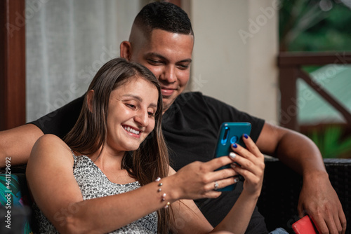 Pareja joven  sonriente disfrutando juntos mientras observan el celular photo