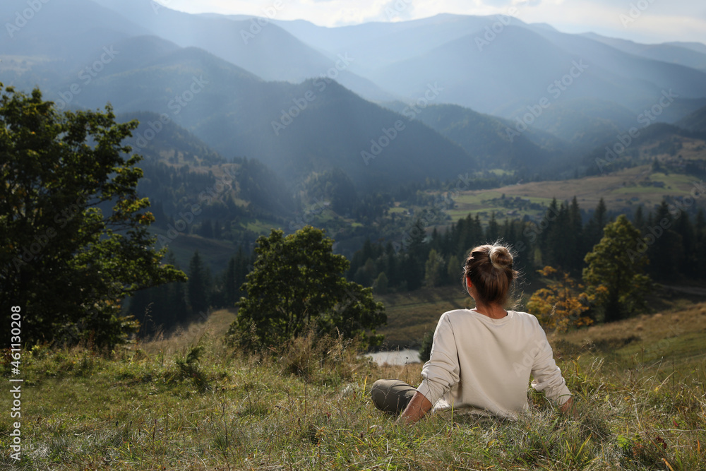 Woman enjoying beautiful mountain landscape, back view. Space for text