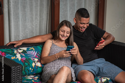 Pareja sonriente sentados utilizando sus celulares