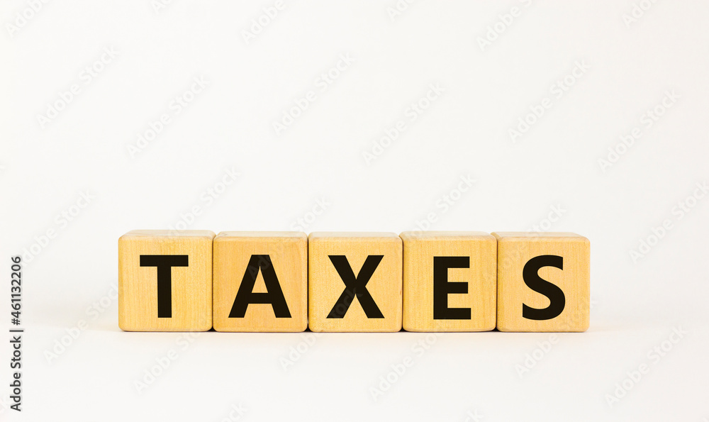 Taxes symbol. The concept word 'taxes' on wooden cubes on a beautiful white table. White background. Business and taxes concept. Copy space. Taxes symbol. The concept word 'taxes' on wooden cubes on a beautiful white table. White background. Business and taxes concept. Copy space.