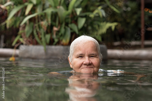 Fototapeta Naklejka Na Ścianę i Meble -  Beautiful smiling old lady enjoying a natural hot spring pool. 