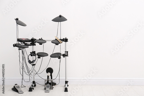 Modern electronic drum kit near white wall indoors, space for text. Musical instrument