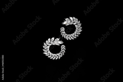 Round Silver earrings with jewels on the black background. Fashion