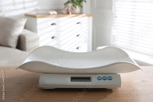 Modern digital baby scales on wooden table in room