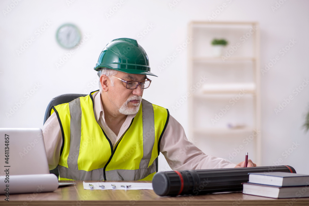 Old male architect working in the office Old male architect working in the office